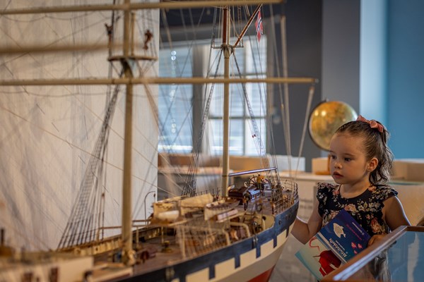 Jente studerer seilskutemodell inne på museet.